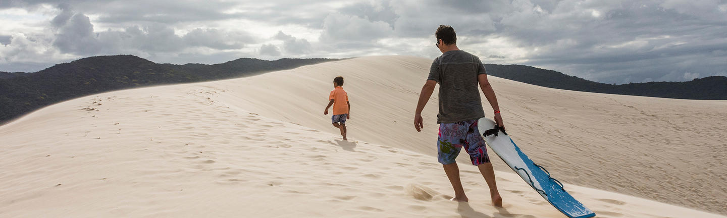 Travel insurance sandboarding, father and son, Brazil
